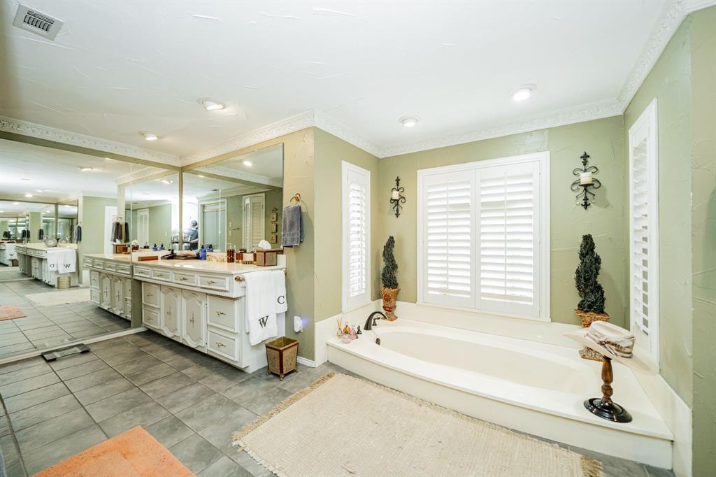 9511 Fallbrook Drive Dallas, TX 75243 - Photo 29 of 40 a bathroom with a bathtub a sink a mirror and a shower