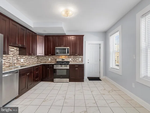 a large kitchen with a stove top oven a sink dishwasher and a refrigerator with wooden cabinets