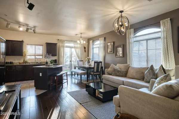 a living room with couches a dining table chairs kitchen view with wooden floor and furniture