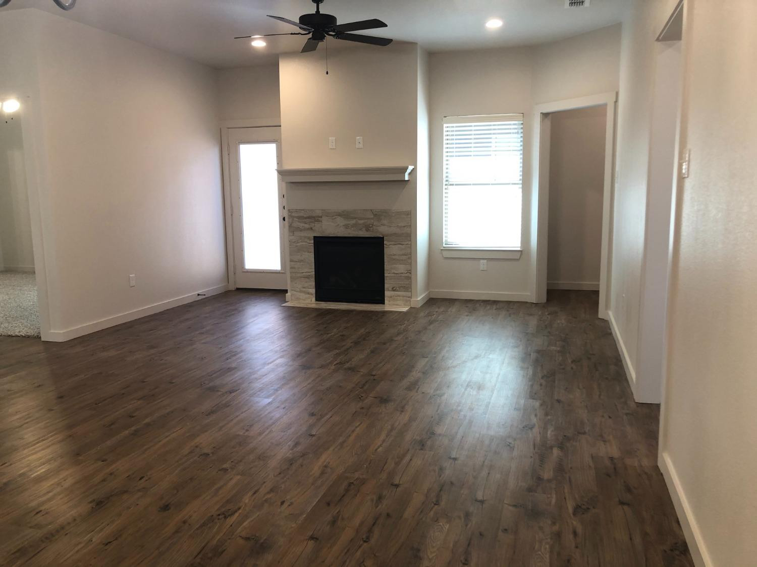 2723 137th Street Lubbock, TX 79423 - Photo 3 of 19 an empty room with wooden floor a fireplace and windows