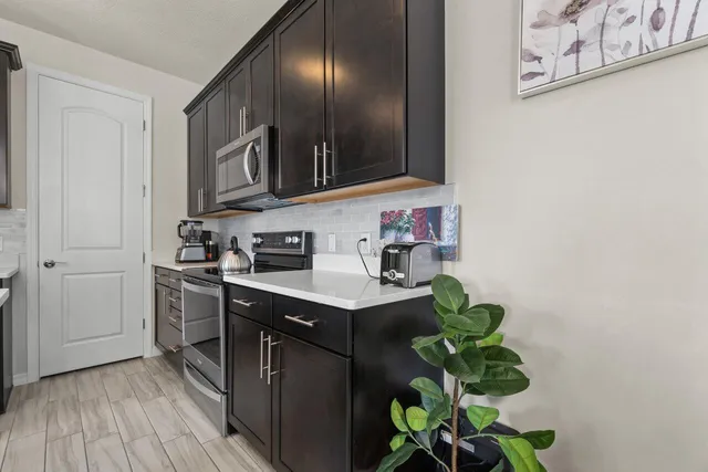 a kitchen with stainless steel appliances a refrigerator a sink a stove a dining table and chairs