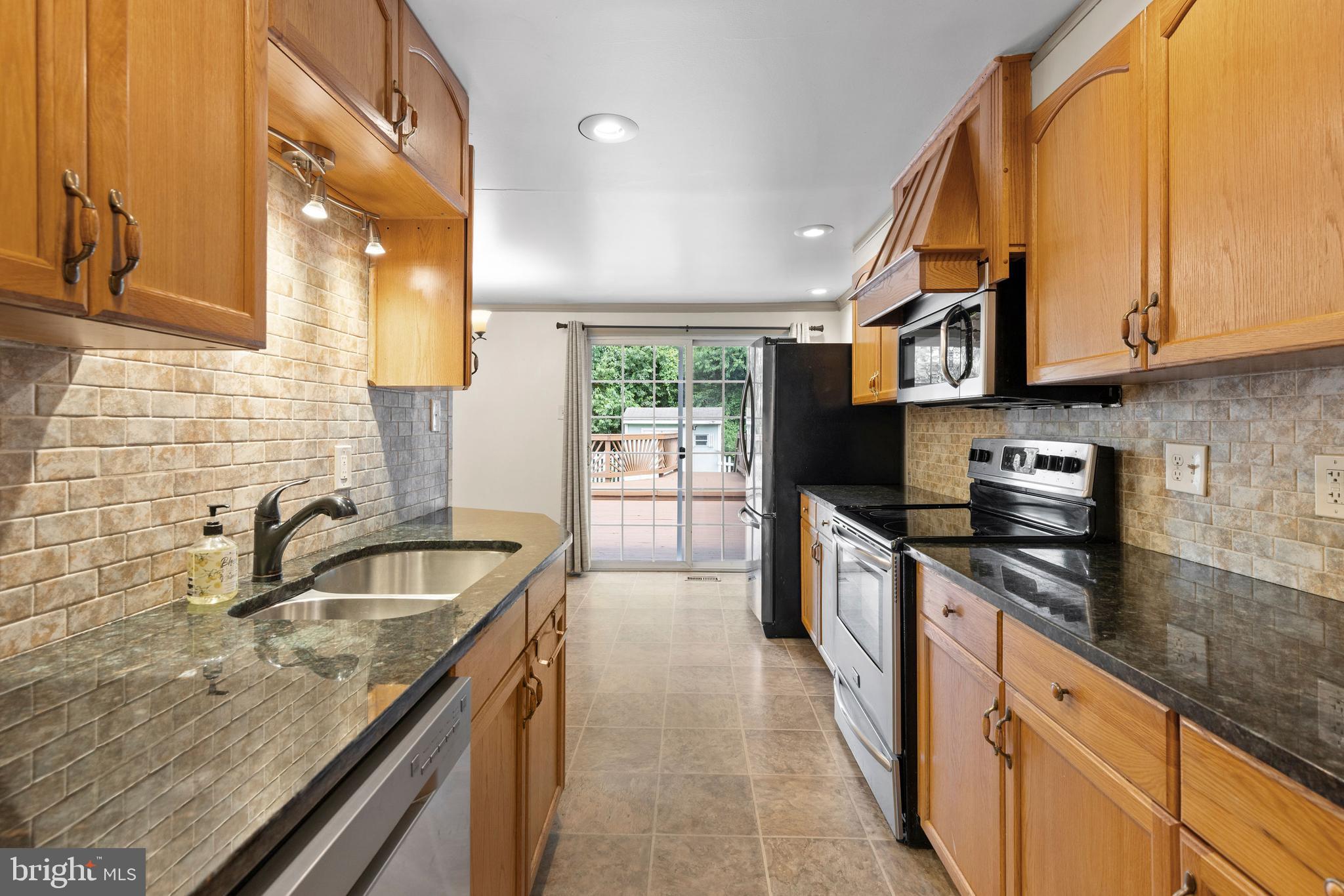 a kitchen with stainless steel appliances granite countertop a sink a stove and a microwave