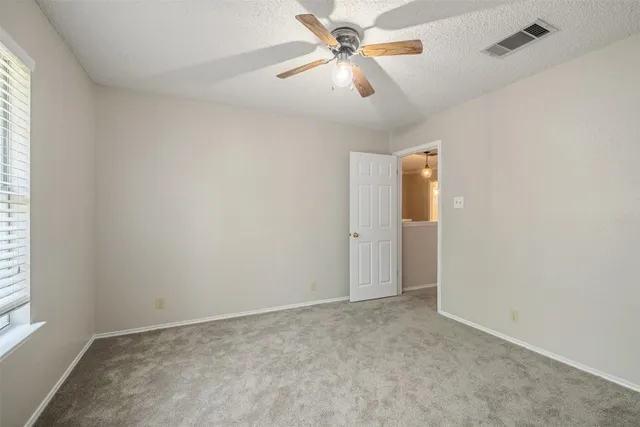 an empty room with chandelier fan and windows
