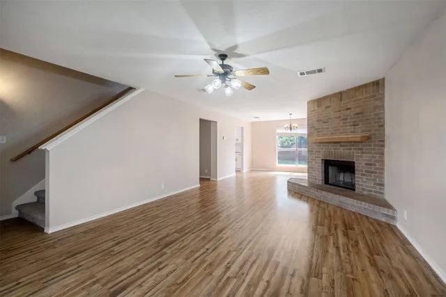 a view of a livingroom with wooden floor a ceiling fan and a fireplace