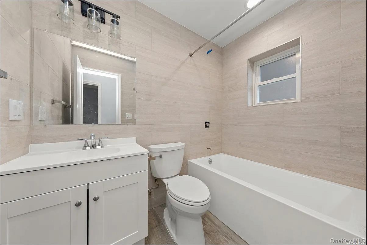 32-17 105th Street, Unit 2F Queens, NY 11369 - Photo 3 of 4 a bathroom with a toilet a sink a mirror and vanity