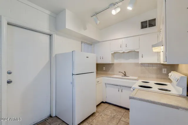 a kitchen with a sink a refrigerator and white cabinets