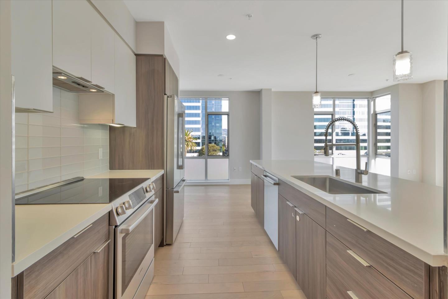 901 Jefferson Street, Unit 510 Oakland, CA 94607 - Photo 7 of 15 a large kitchen with kitchen island a large window a sink and stainless steel appliances