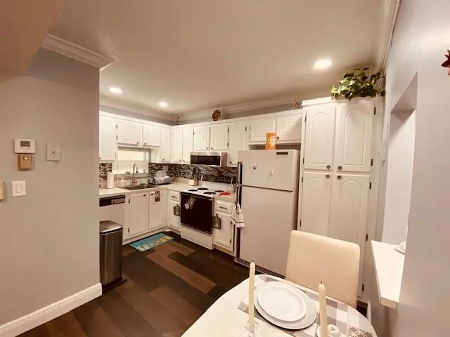 a kitchen with a refrigerator a white stove top oven and sink
