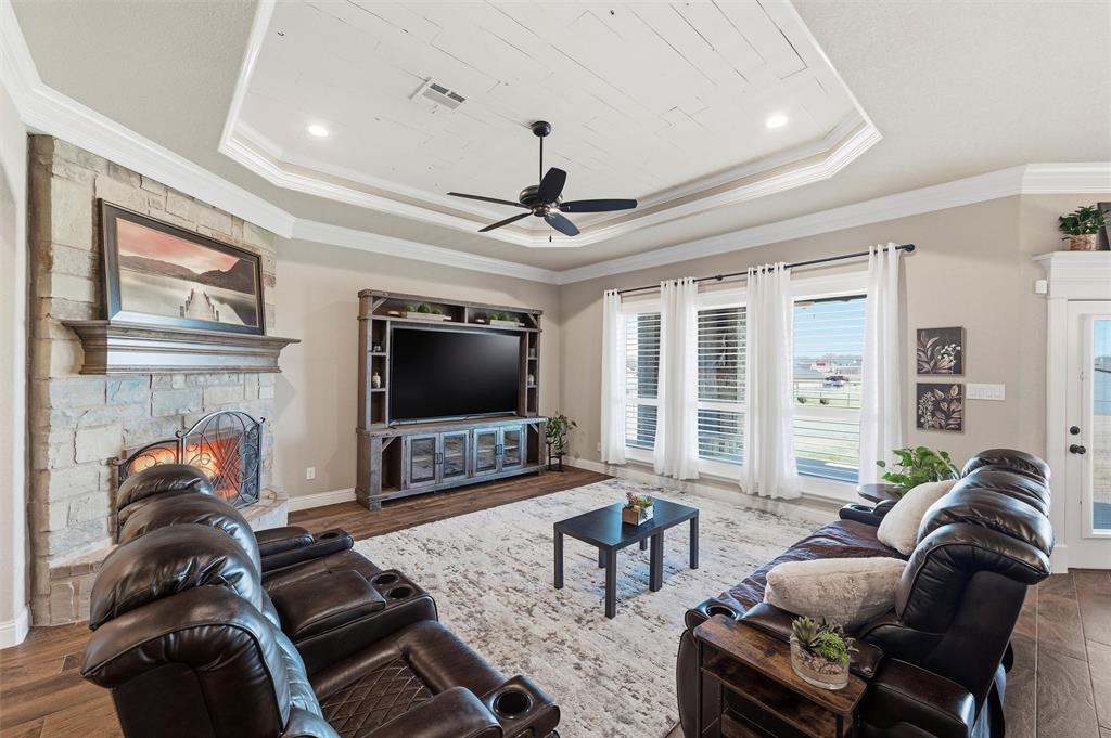 121 Bluff Ridge Court Paradise, TX 76073 - Photo 5 of 33 Living room with dark wood finished floors, a stone fireplace, crown molding, and a ceiling fan