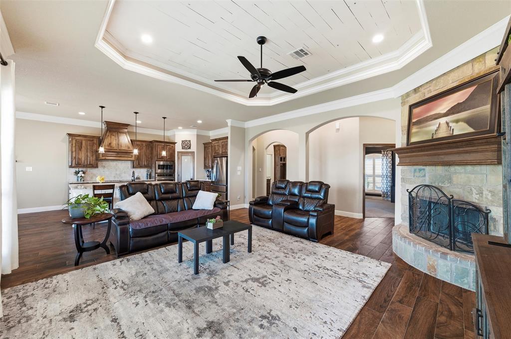 121 Bluff Ridge Court Paradise, TX 76073 - Photo 6 of 33 Living area with arched walkways, dark wood-type flooring, a tray ceiling, ornamental molding, and ceiling fan
