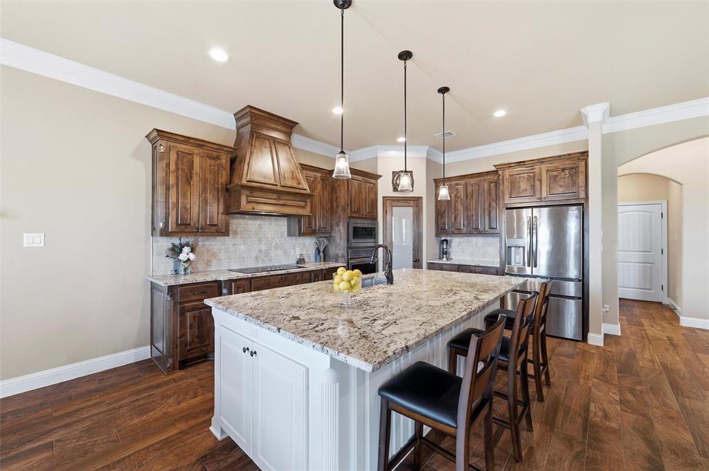 121 Bluff Ridge Court Paradise, TX 76073 - Photo 7 of 33 Kitchen with arched walkways, tasteful backsplash, appliances with stainless steel finishes, white cabinets, and crown molding