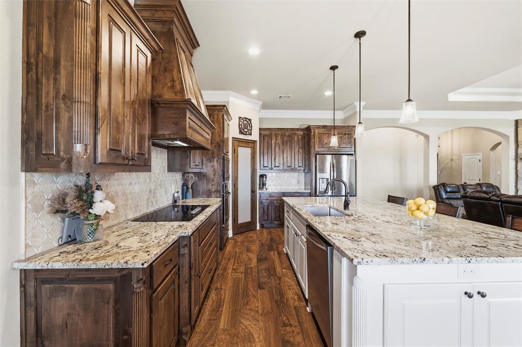 121 Bluff Ridge Court Paradise, TX 76073 - Photo 8 of 33 Kitchen with dark brown cabinetry, arched walkways, pendant lighting, light stone countertops, and dark wood-style flooring