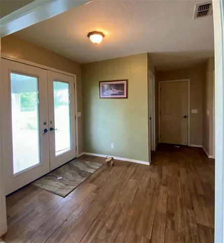 an empty room with wooden floor and windows