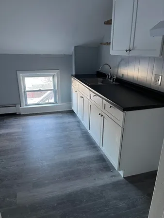 a kitchen with granite countertop a stove and a wooden floors
