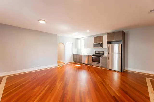 a view of a kitchen with wooden floor and stainless steel appliances