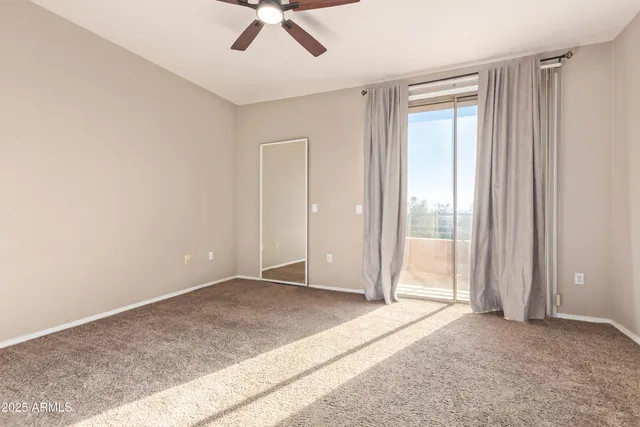a view of an empty room with closet and mirror
