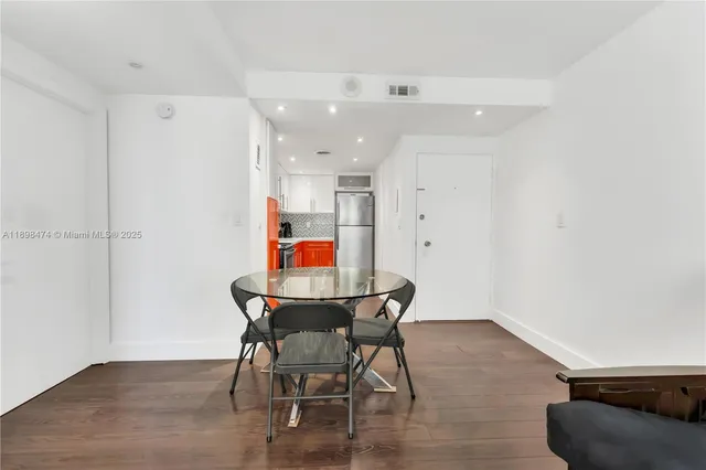 a living room with stainless steel appliances kitchen island granite countertop a dining table chairs and a refrigerator