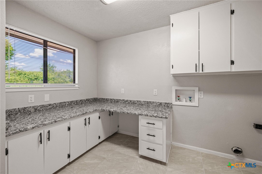 1120 Old Mill Road Salado, TX 76571 - Photo 18 of 42 a kitchen with granite countertop white cabinets and window