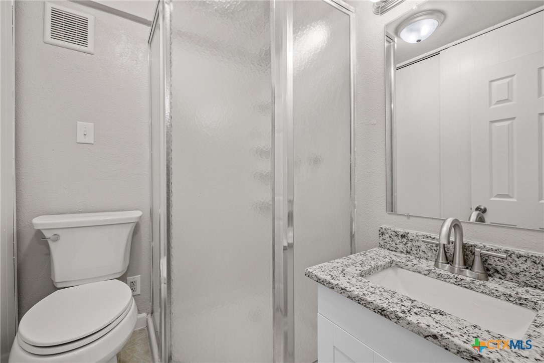 1120 Old Mill Road Salado, TX 76571 - Photo 27 of 42 a bathroom with a granite countertop toilet a sink and a mirror