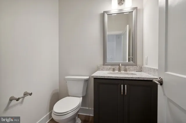 a bathroom with a granite countertop toilet a sink and mirror
