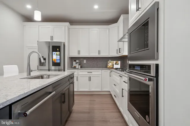 a kitchen with granite countertop a sink stainless steel appliances and white cabinets