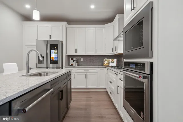 a kitchen with granite countertop a sink stainless steel appliances and white cabinets