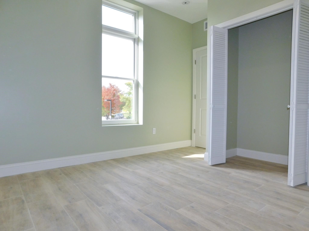 10 Roxbury Street, Unit 8 Boston, MA 02119 - Photo 3 of 10 an empty room with wooden floor and windows