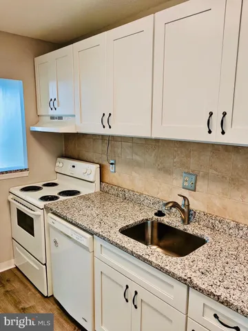 a kitchen with granite countertop white cabinets and white appliances