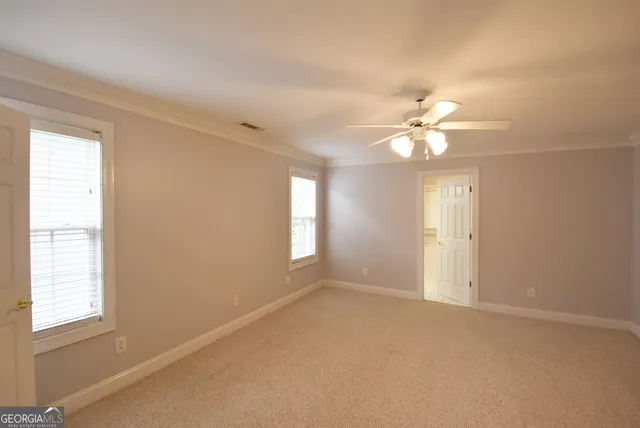 an empty room with windows and chandelier fan