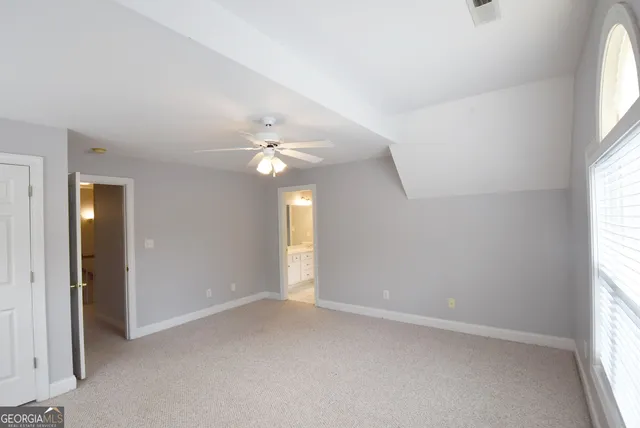 an empty room with windows and chandelier fan
