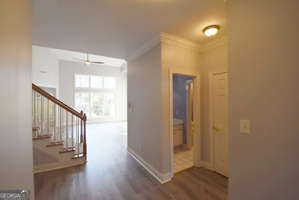 a view of hallway with wooden floor and a bathroom