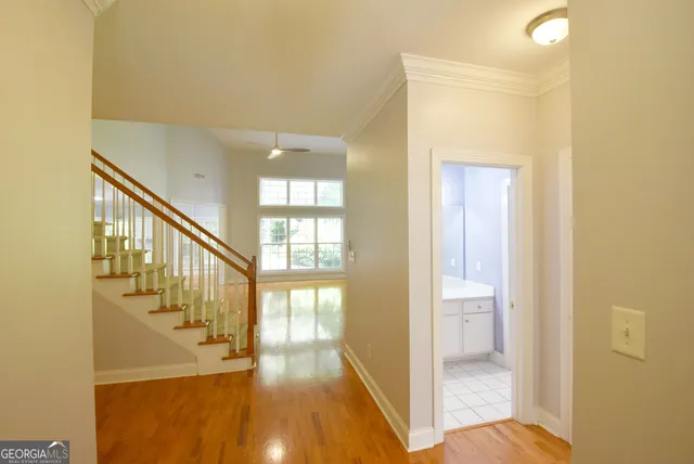 a view of hallway with wooden floor and a bathroom
