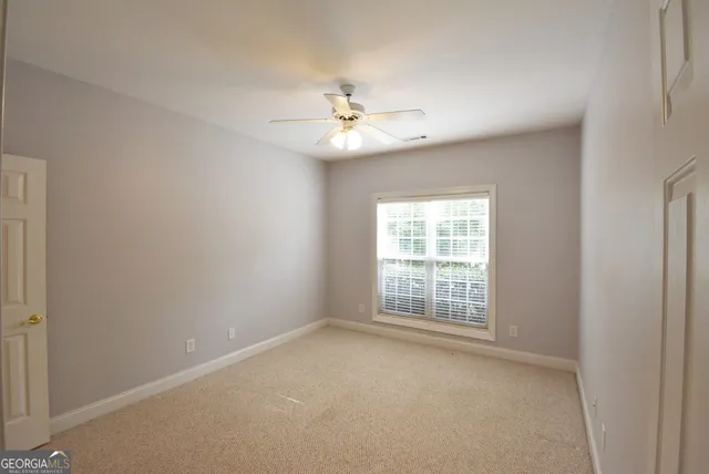 an empty room with windows and fan