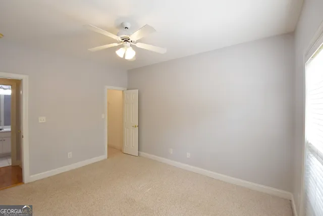 an empty room with a window and ceiling fan