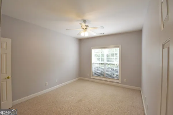 an empty room with a window and ceiling fan