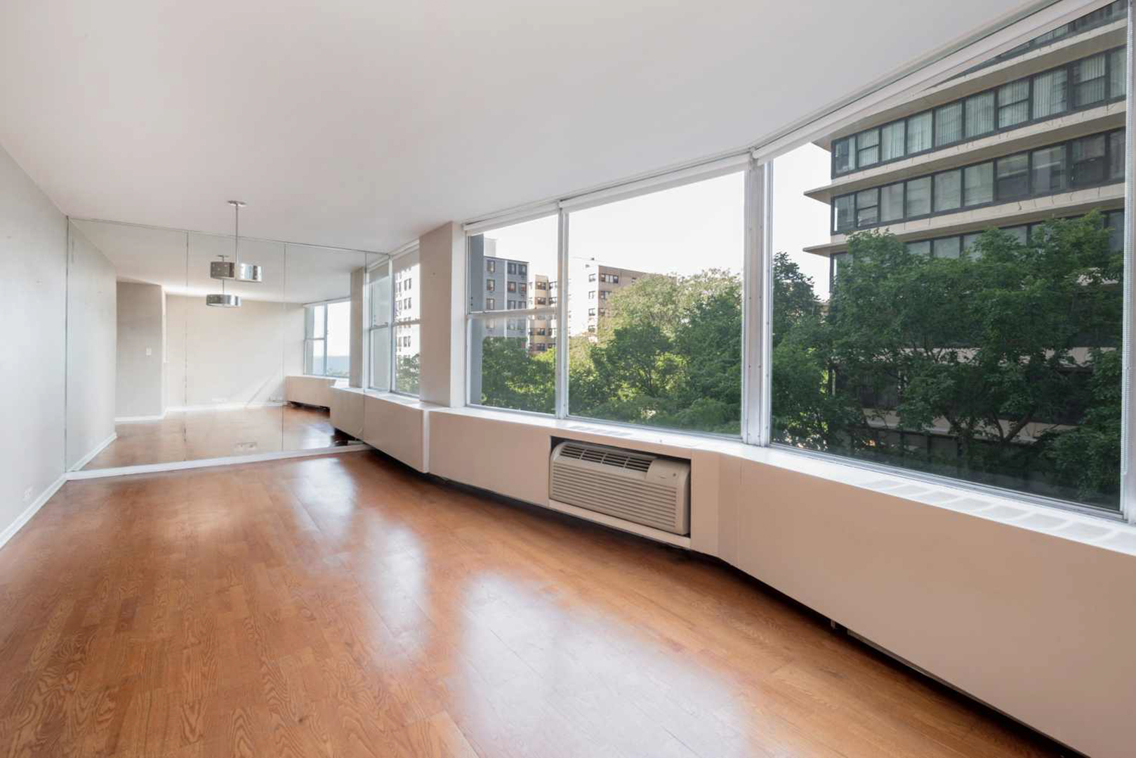 5757 North Sheridan Road, Unit 4E Chicago, IL 60660 - Photo 4 of 11 a view of an empty room with a window and wooden floor