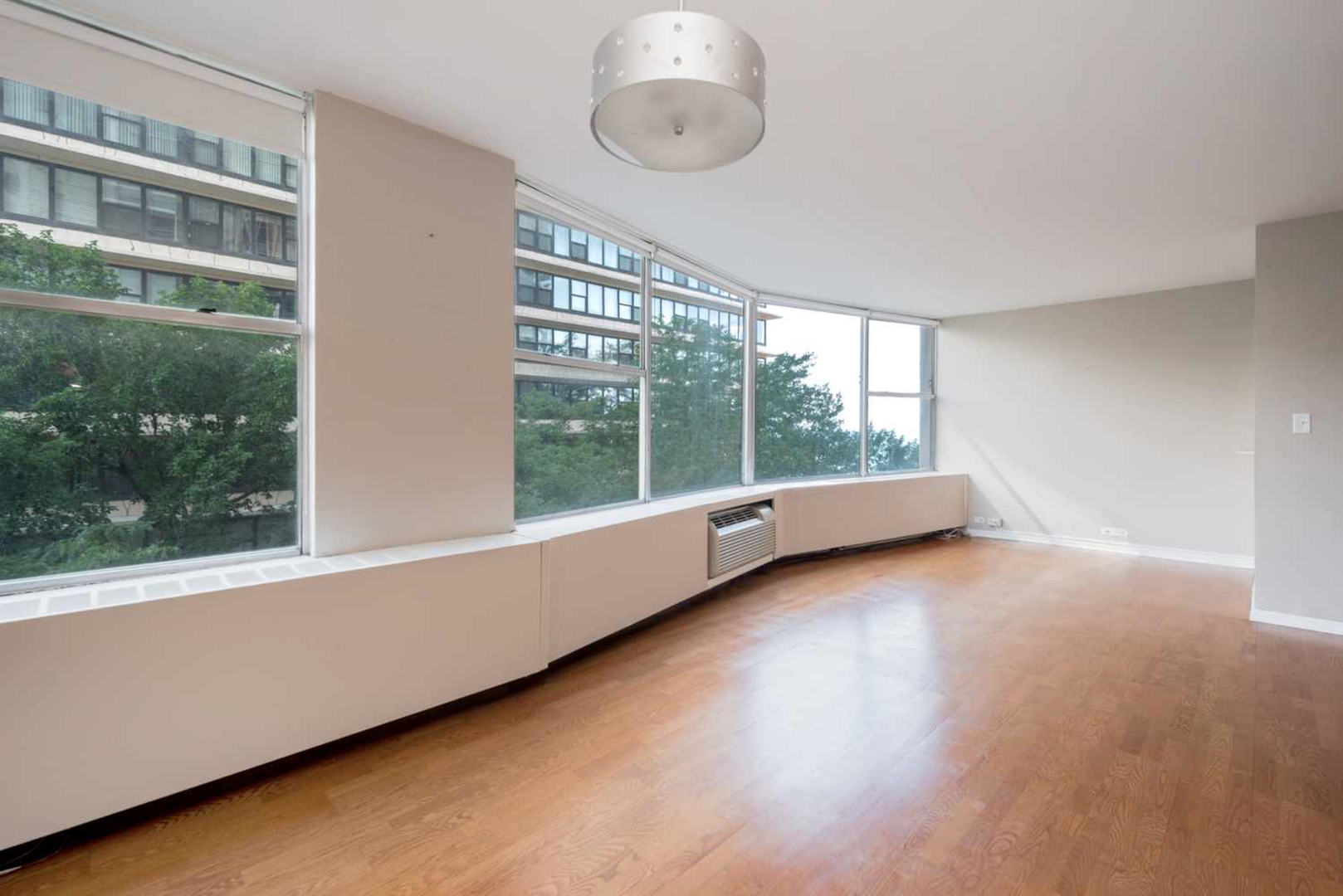 5757 North Sheridan Road, Unit 4E Chicago, IL 60660 - Photo 5 of 11 a view of an empty room with a window and wooden floor