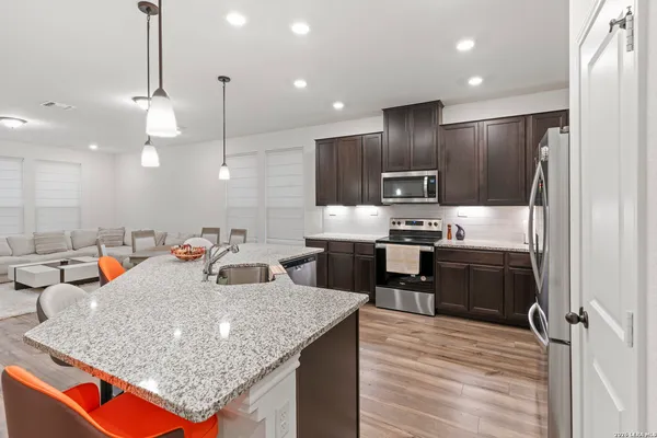 a kitchen with kitchen island granite countertop wooden cabinets and refrigerator