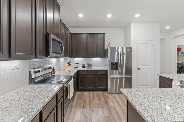 a kitchen with kitchen island granite countertop stainless steel appliances and wooden cabinets