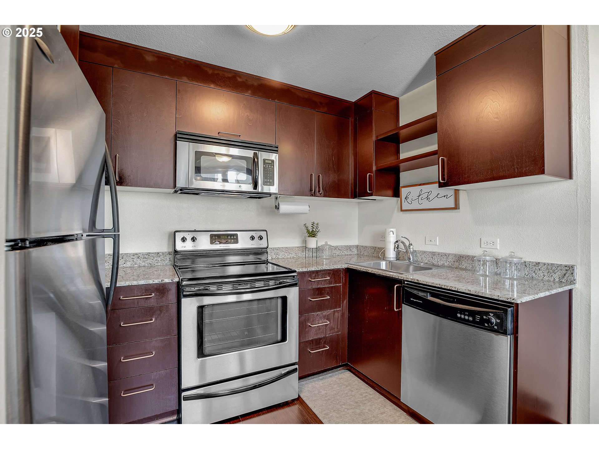 255 Southwest Harrison Street, Unit 17F Portland, OR 97201 - Photo 7 of 31 a kitchen with stainless steel appliances granite countertop a stove a sink and a microwave