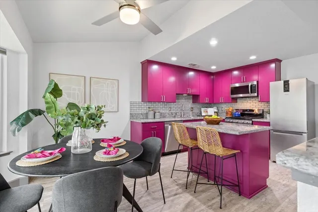 a kitchen with stainless steel appliances kitchen island granite countertop a dining table and chairs
