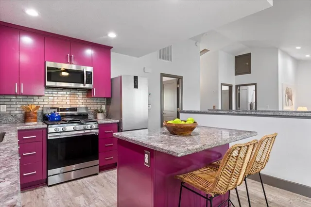 a kitchen with stainless steel appliances granite countertop a stove a sink dishwasher a refrigerator and a dining table with chairs