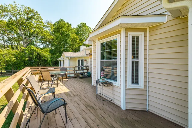 a view of a house with a yard deck and a large tree