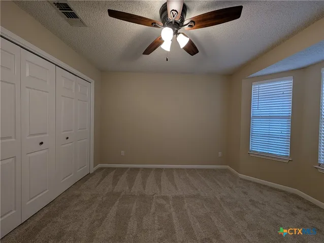 an empty room with windows and fan