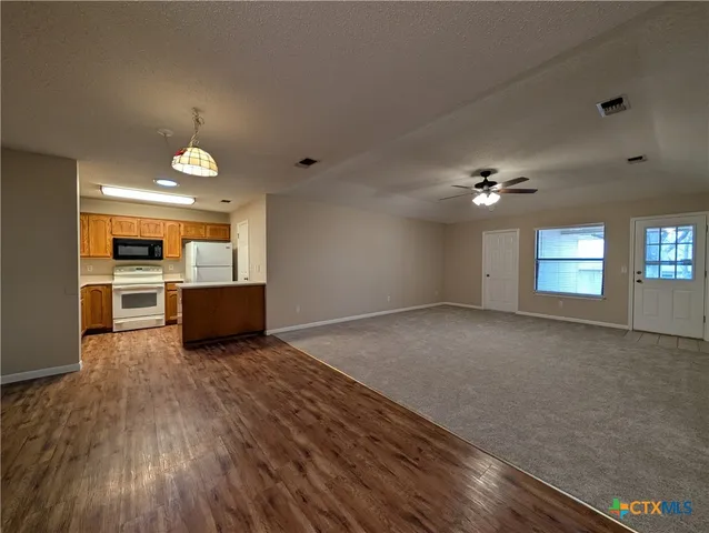 a view of a big room with wooden floor and a kitchen