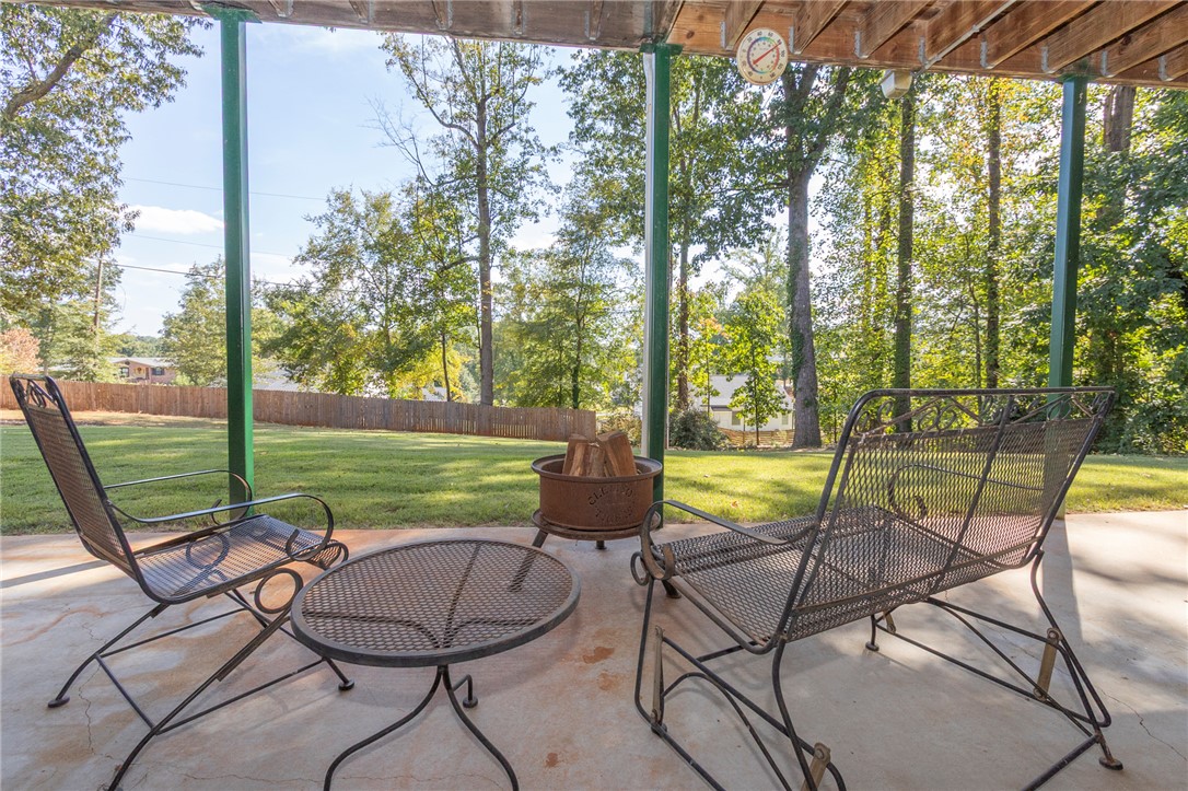 608 Robin Hood Lane Anderson, SC 29621 - Photo 27 of 36 A covered concrete patio overlooks the deep green yard bounded by a wooden fence.