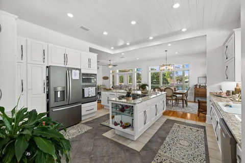 a kitchen with stainless steel appliances a stove a sink dishwasher a refrigerator and white cabinets with wooden floor