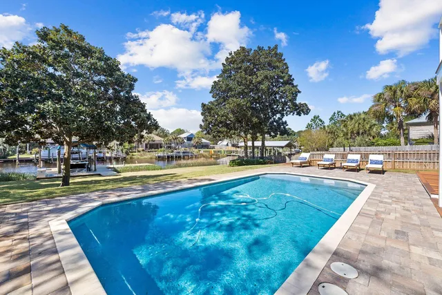 a view of swimming pool with outdoor seating and trees in the background