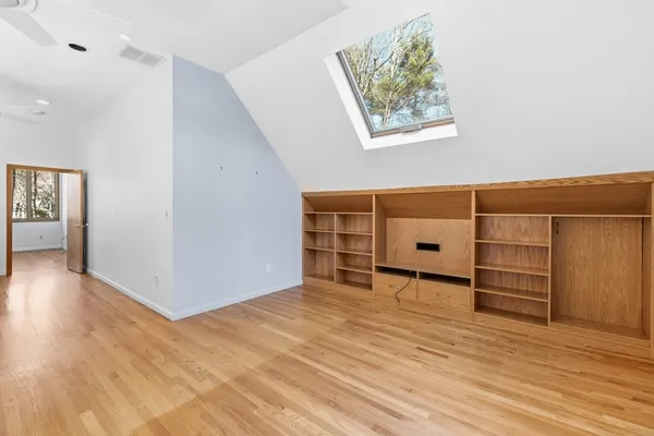 an empty room with wooden floor closet and windows