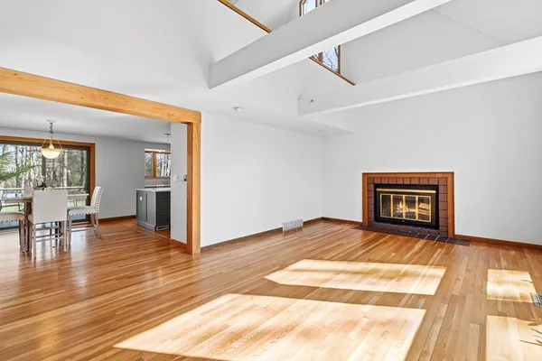 a view of an empty room with wooden floor and a fireplace